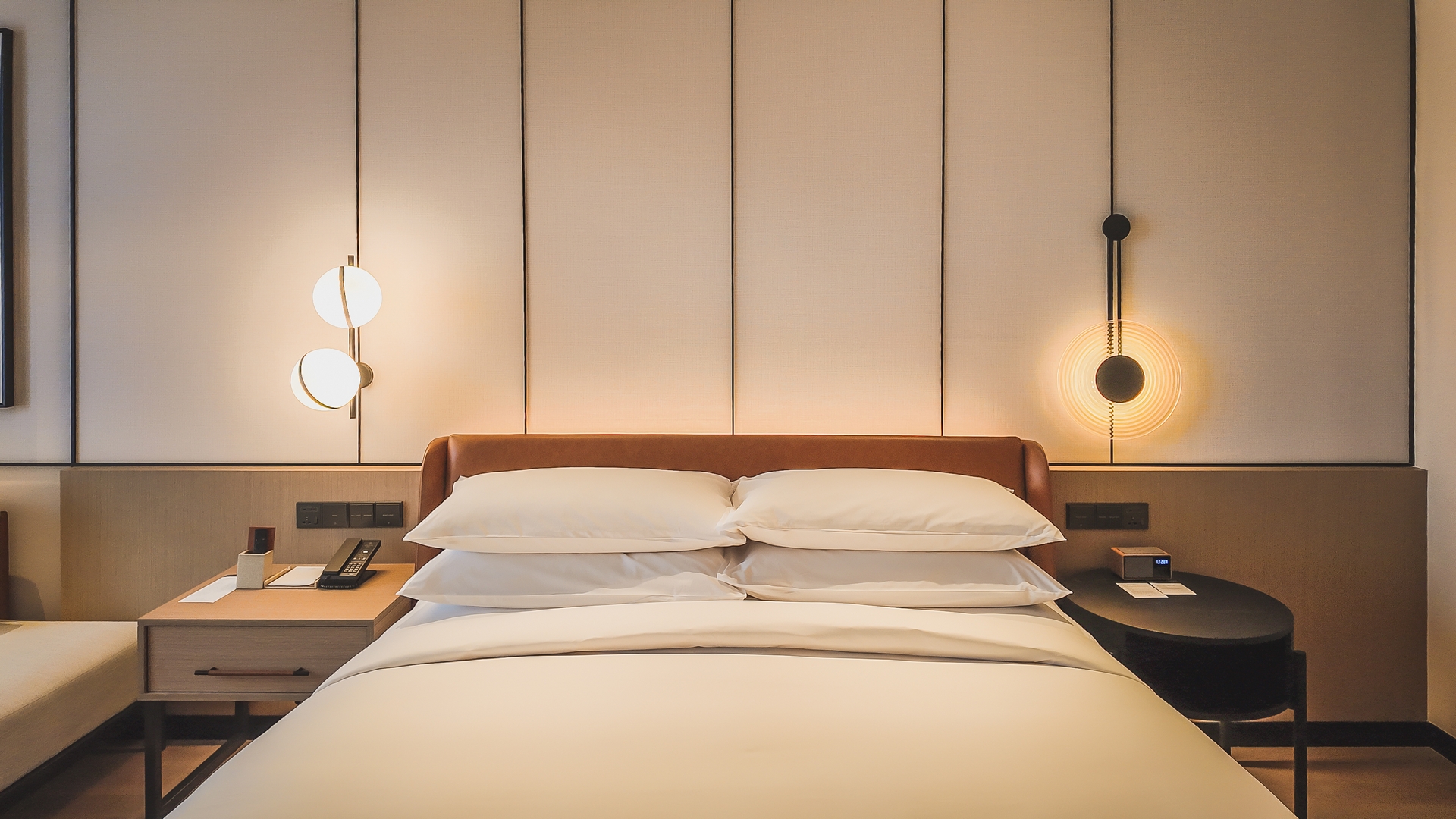 不对称床头设计，配有对比灯具和桌子，呈现现代极简风格，新山喜来登酒店。